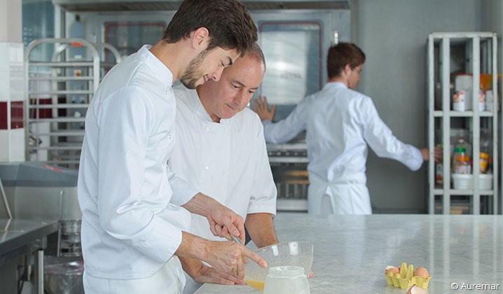 Apprenti cuisinier écoutant son maître d'apprentissage